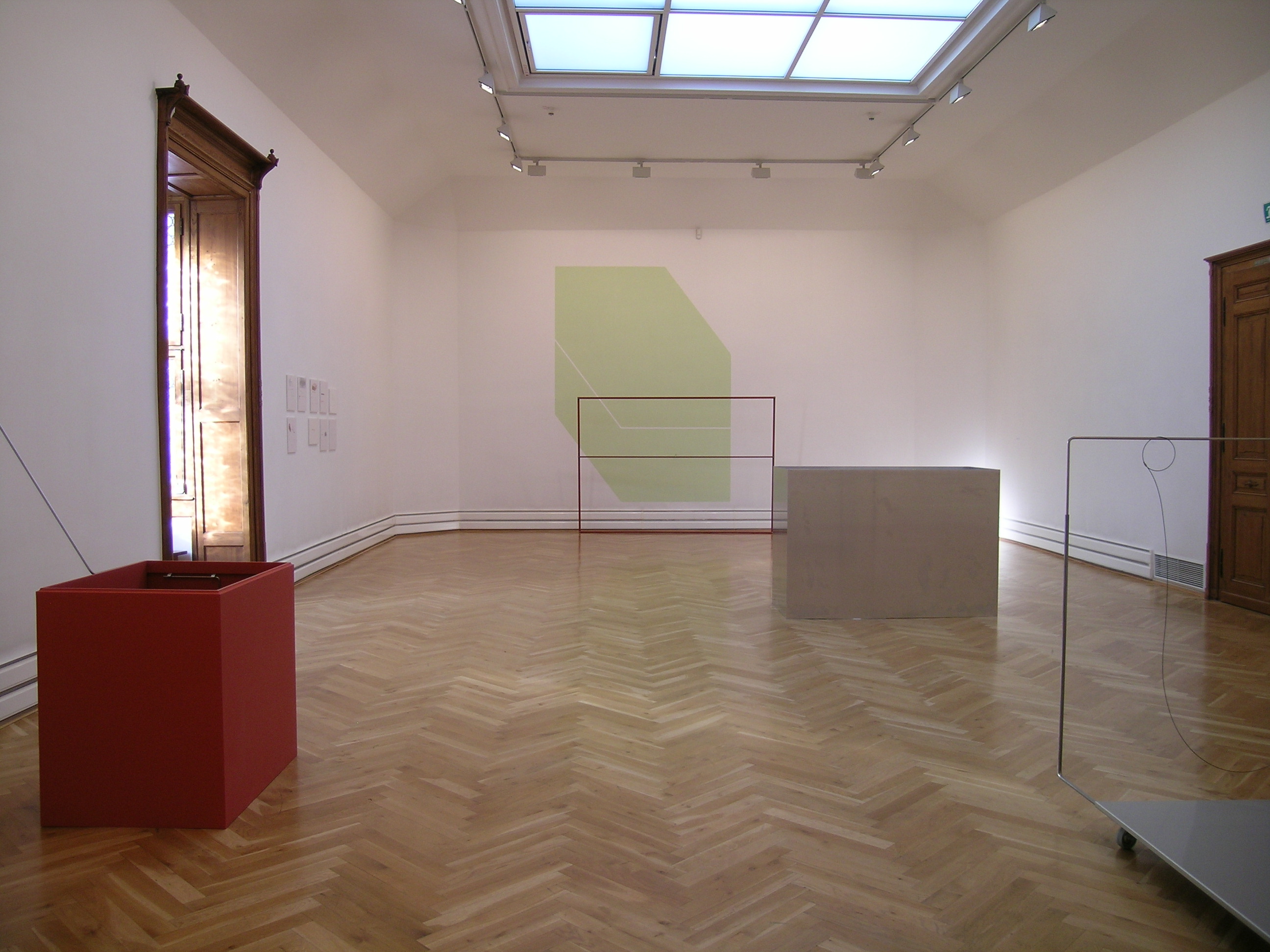 KI generiert: Das Bild zeigt einen minimalistisch eingerichteten Ausstellungsraum in einer Galerie mit modernen Kunstinstallationen. Der Raum ist hell beleuchtet und verfügt über geometrische Skulpturen und Malereien.