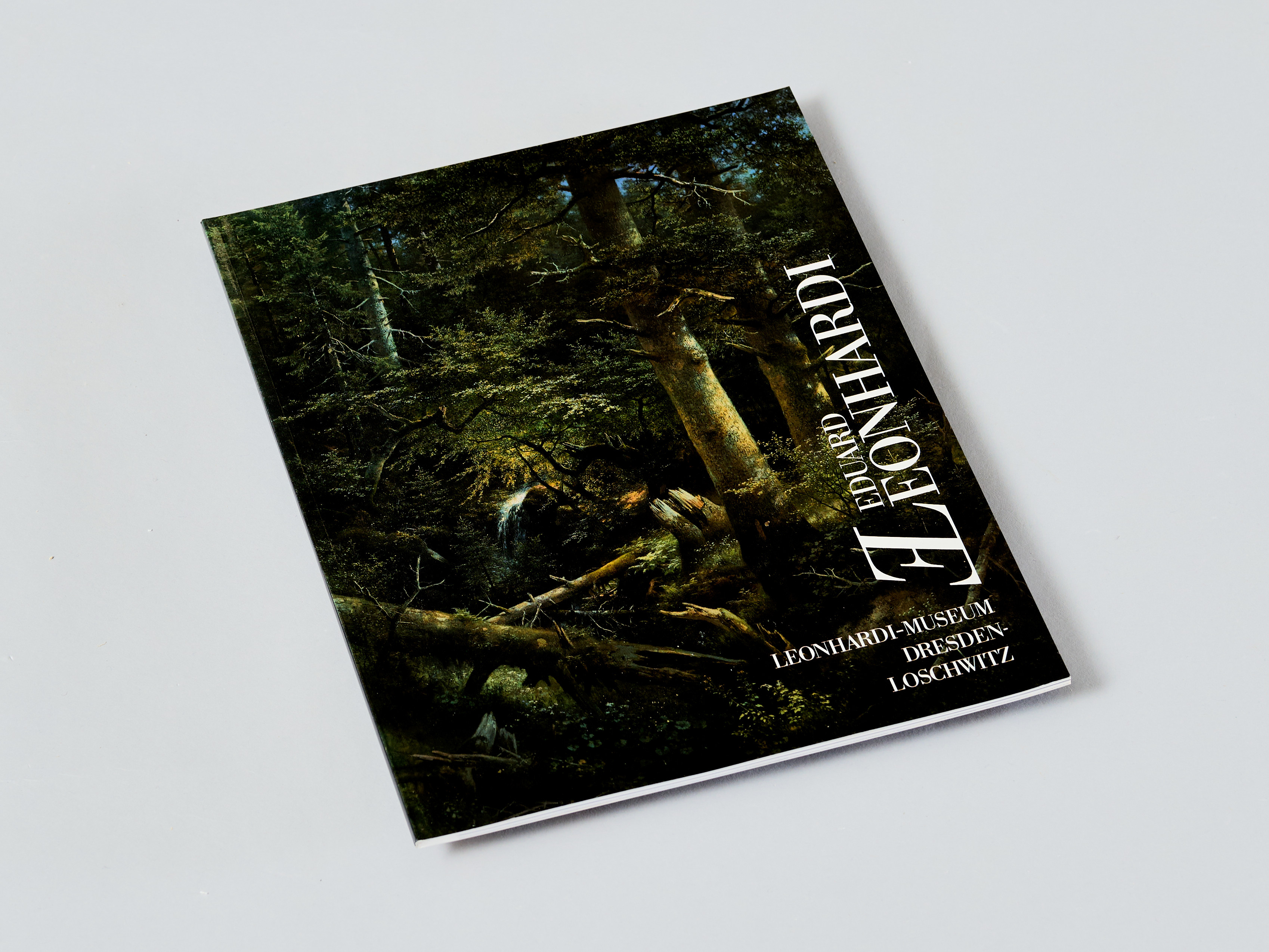 AI generated: The image shows a small book or brochure with a dark green, forest-like cover design set on a neutral background. The cover reads "LEONARDI."