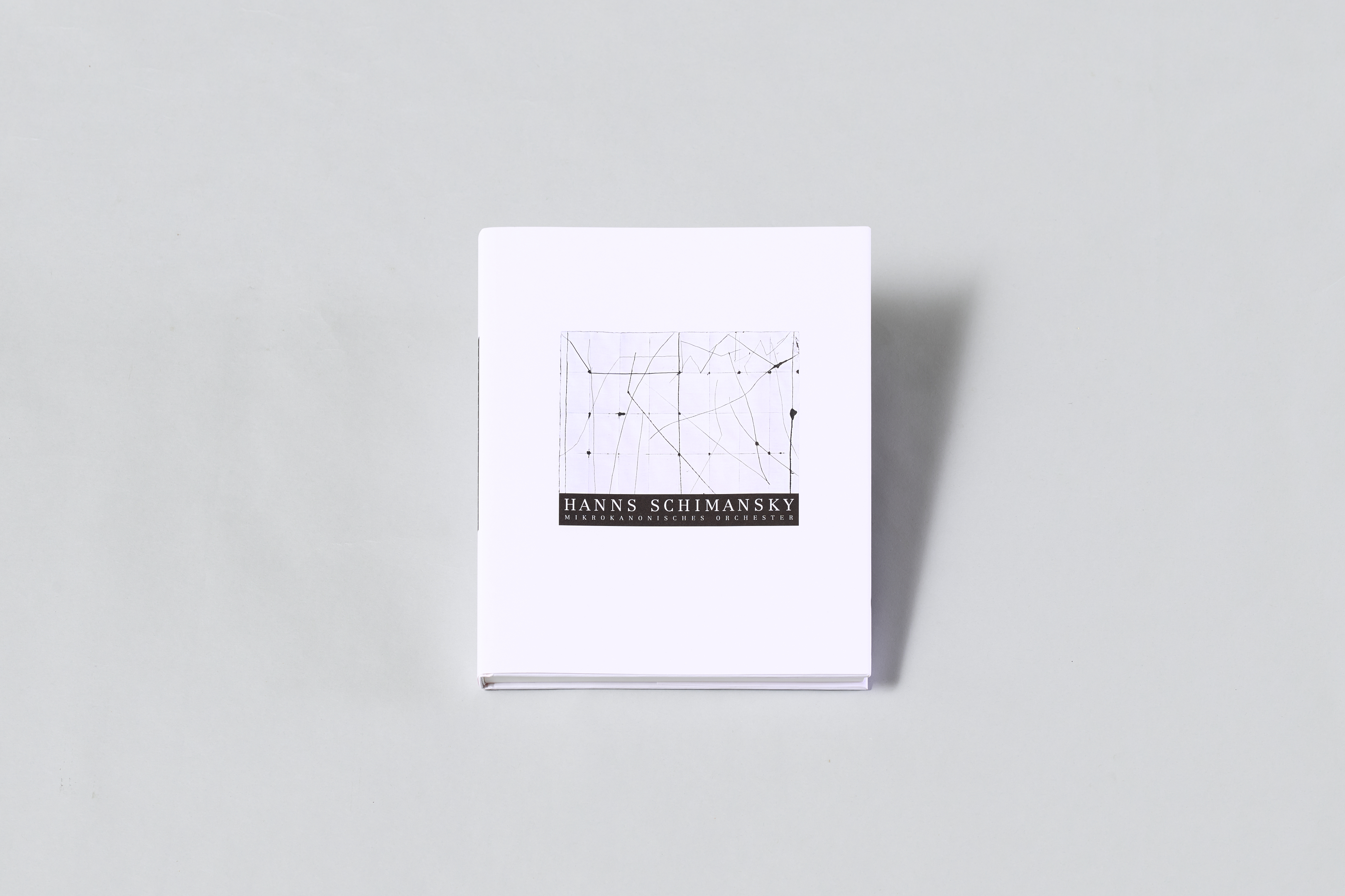 AI generated: The image shows a book with a plain white cover featuring the name "Hanns Schimansky" together with an abstract, line-based design. The focus is on the minimalist design of the book.