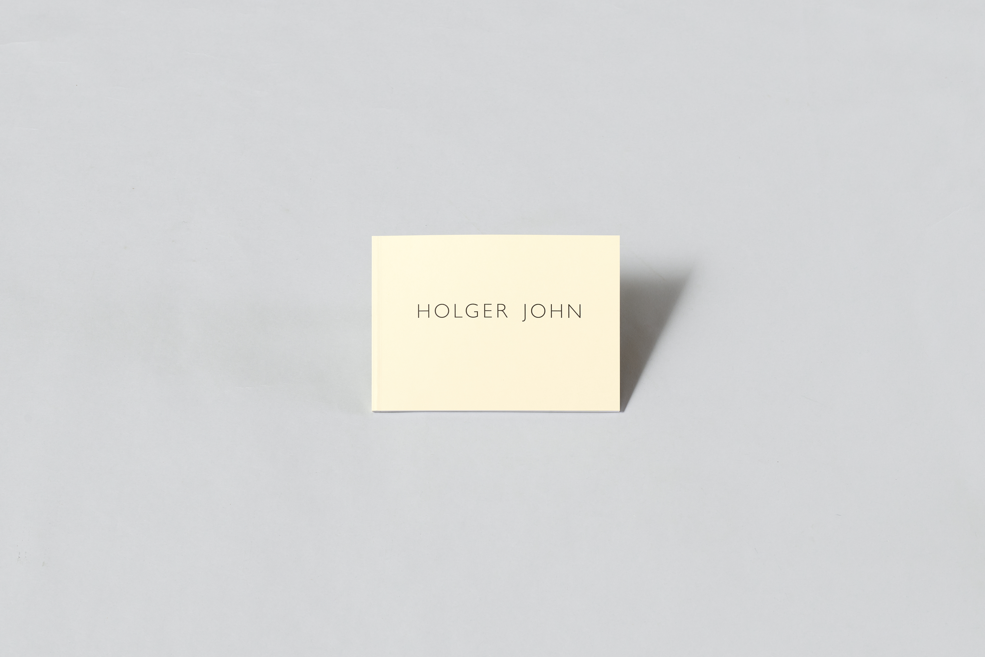 AI generated: The image shows a simple, cream-coloured card with the inscription "HOLGER JOHN" in the centre. The card stands out against a grey background.