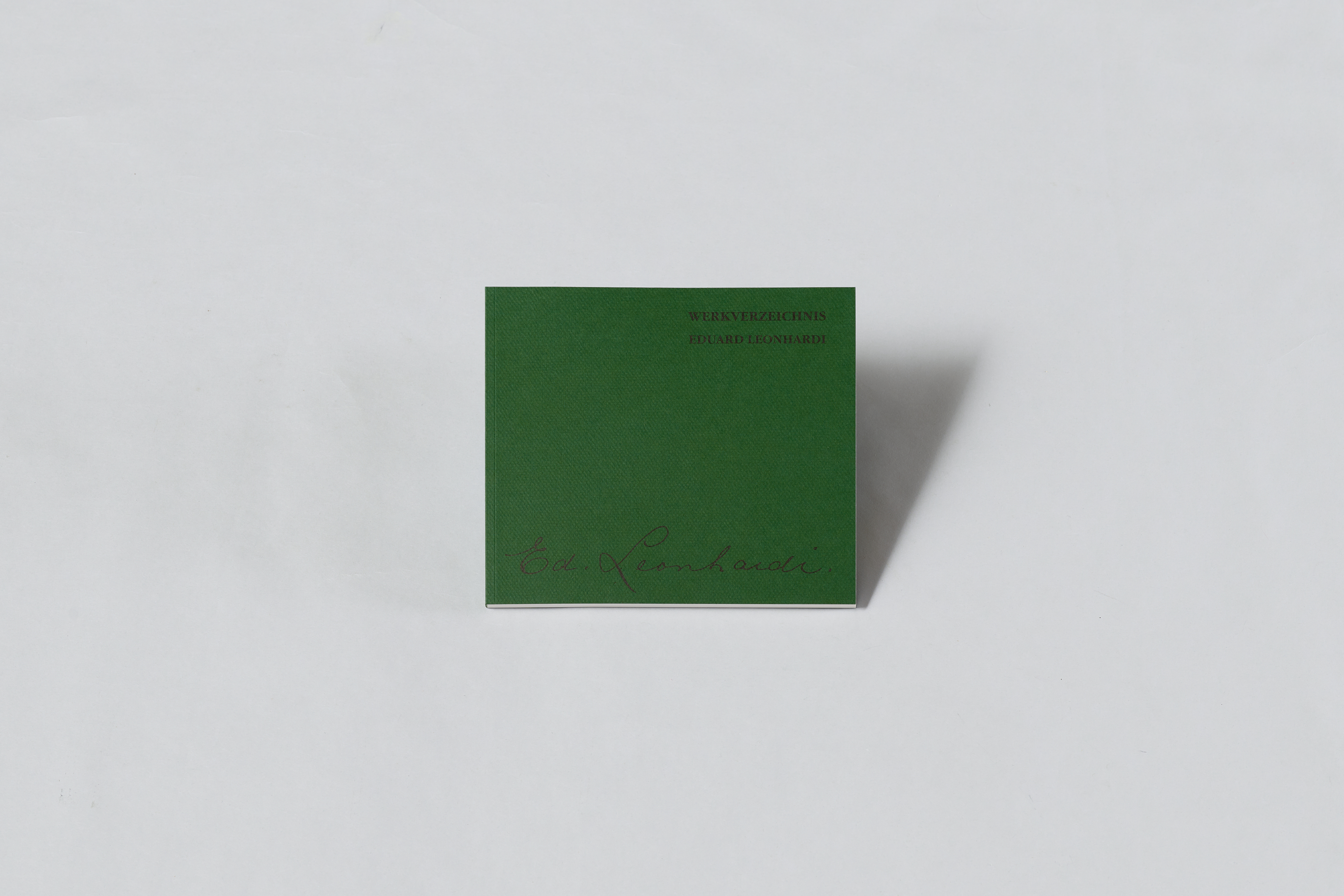 AI generated: The image shows a green book with the inscription "Werkverzeichnis Erhard Leonardi" on the cover. It is lying on a white surface.