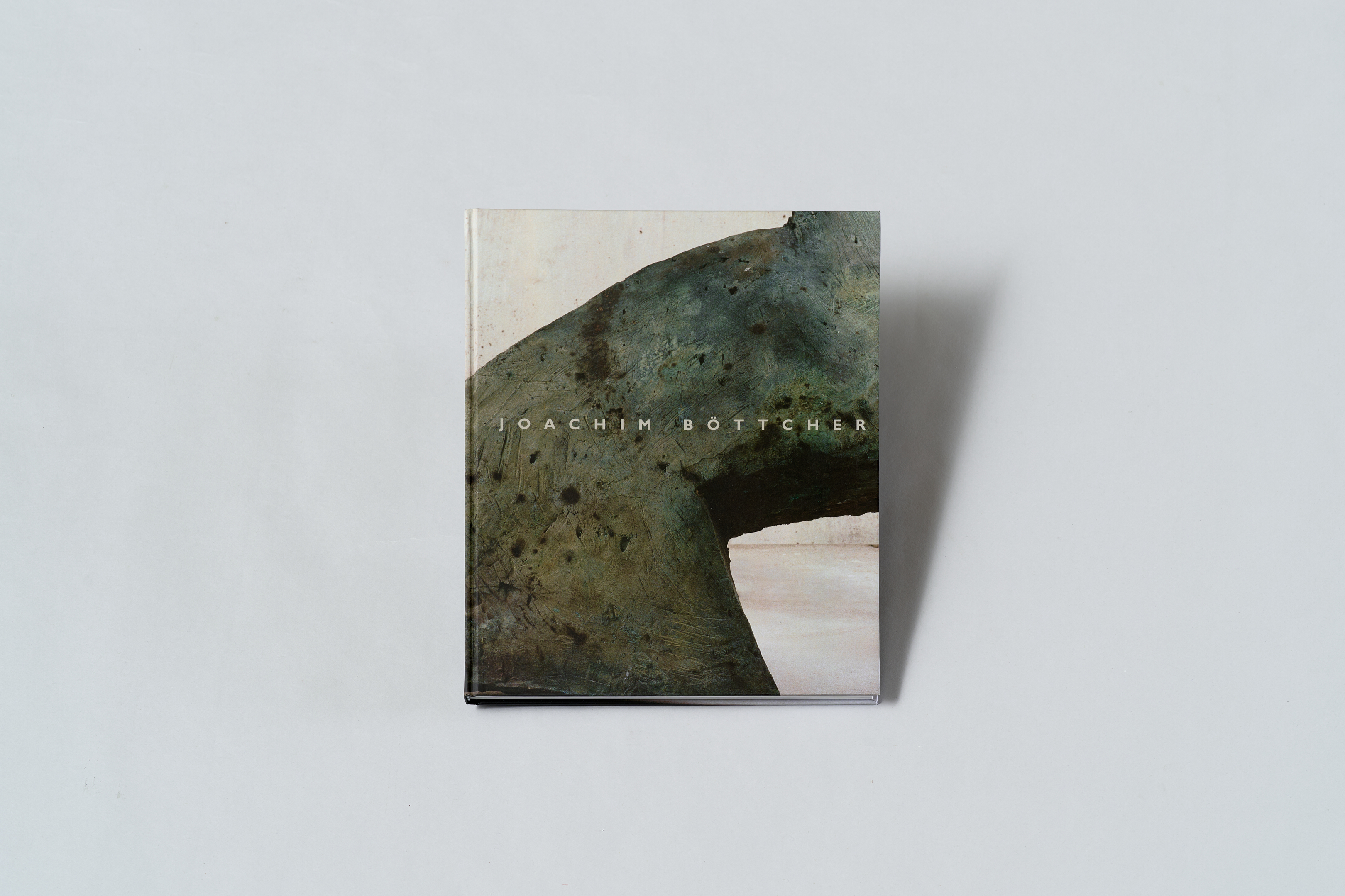 AI generated: The image shows a book with an art design on the cover that depicts abstract shapes in earthy colours. The name "Joachim Böttcher" can be read on the book cover.