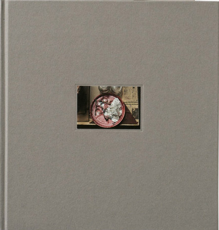 KI generiert: Das Bild zeigt zwei graue Bücher mit kleinen Fenstern auf ihren Covern, durch die ein Teil eines Bildes zu sehen ist. Die Bücher liegen versetzt übereinander.