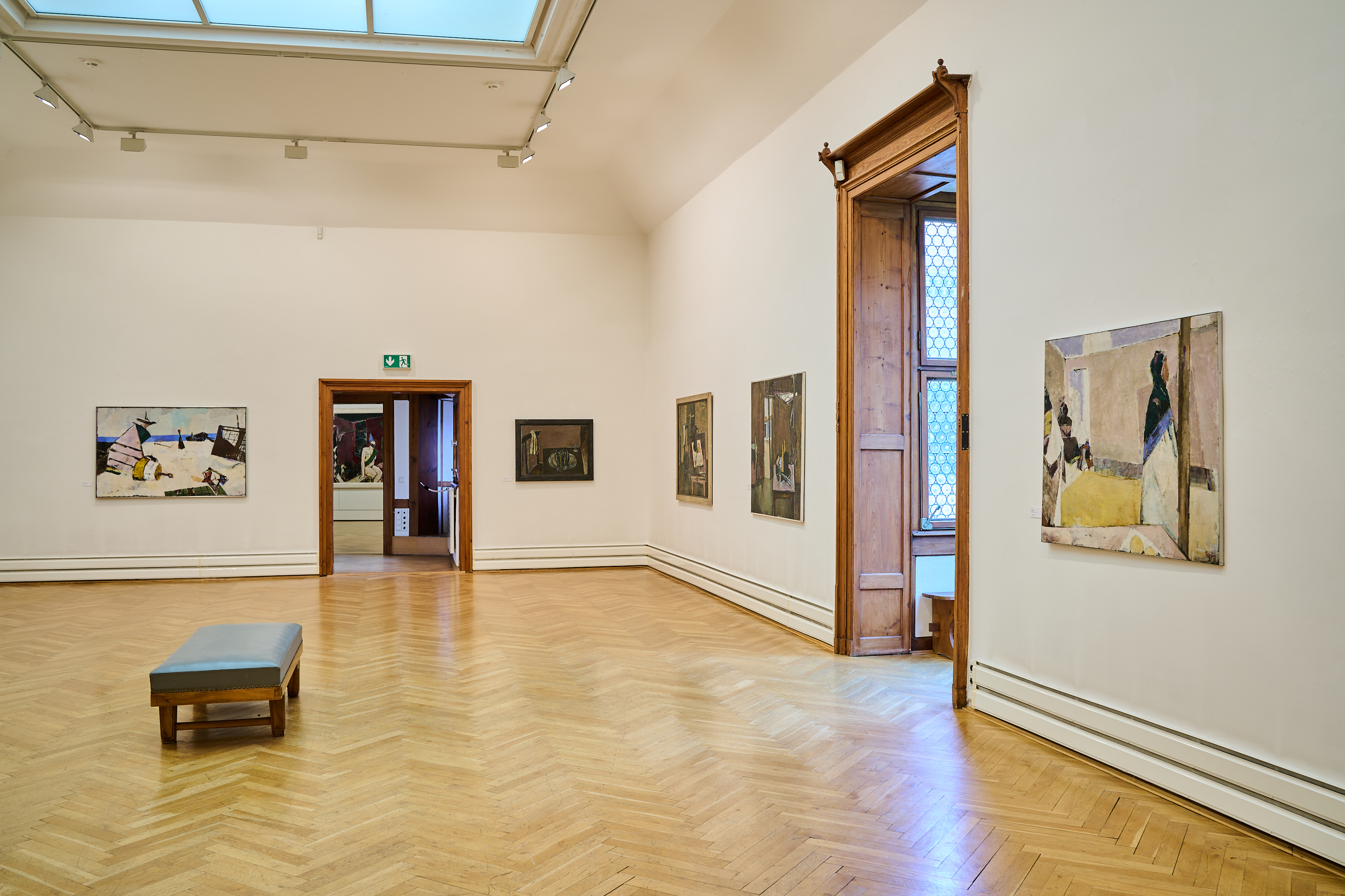 KI generiert: Das Bild zeigt einen Museumsraum mit hölzernem Boden, hellen Wänden, mehreren Gemälden und einer Sitzbank in der Mitte. Türen und ein Fenster mit Holzrahmen sind ebenfalls sichtbar.