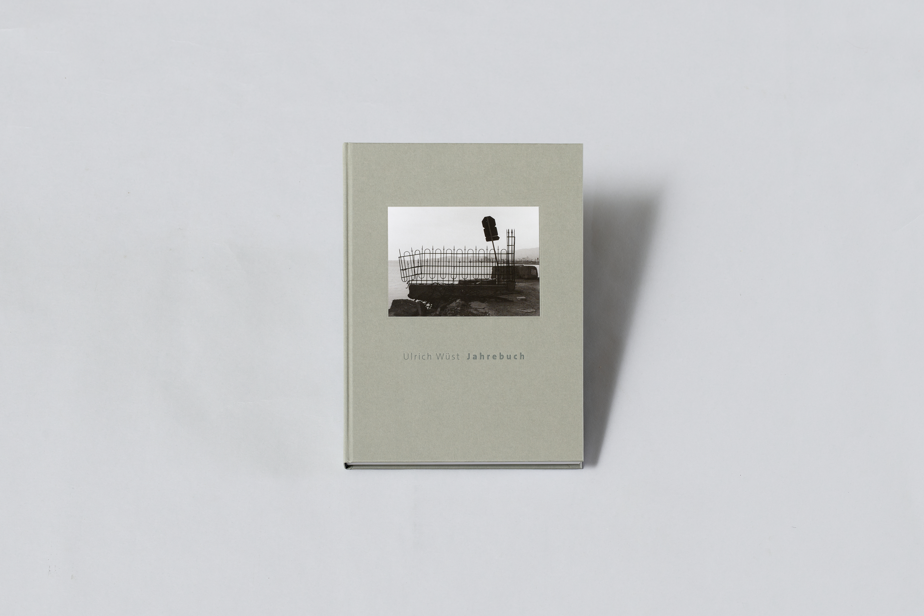 AI generated: The image shows a book with a grey cover and a black and white photograph on the cover. The title of the book is "Ulrich Wüst: Yearbook".