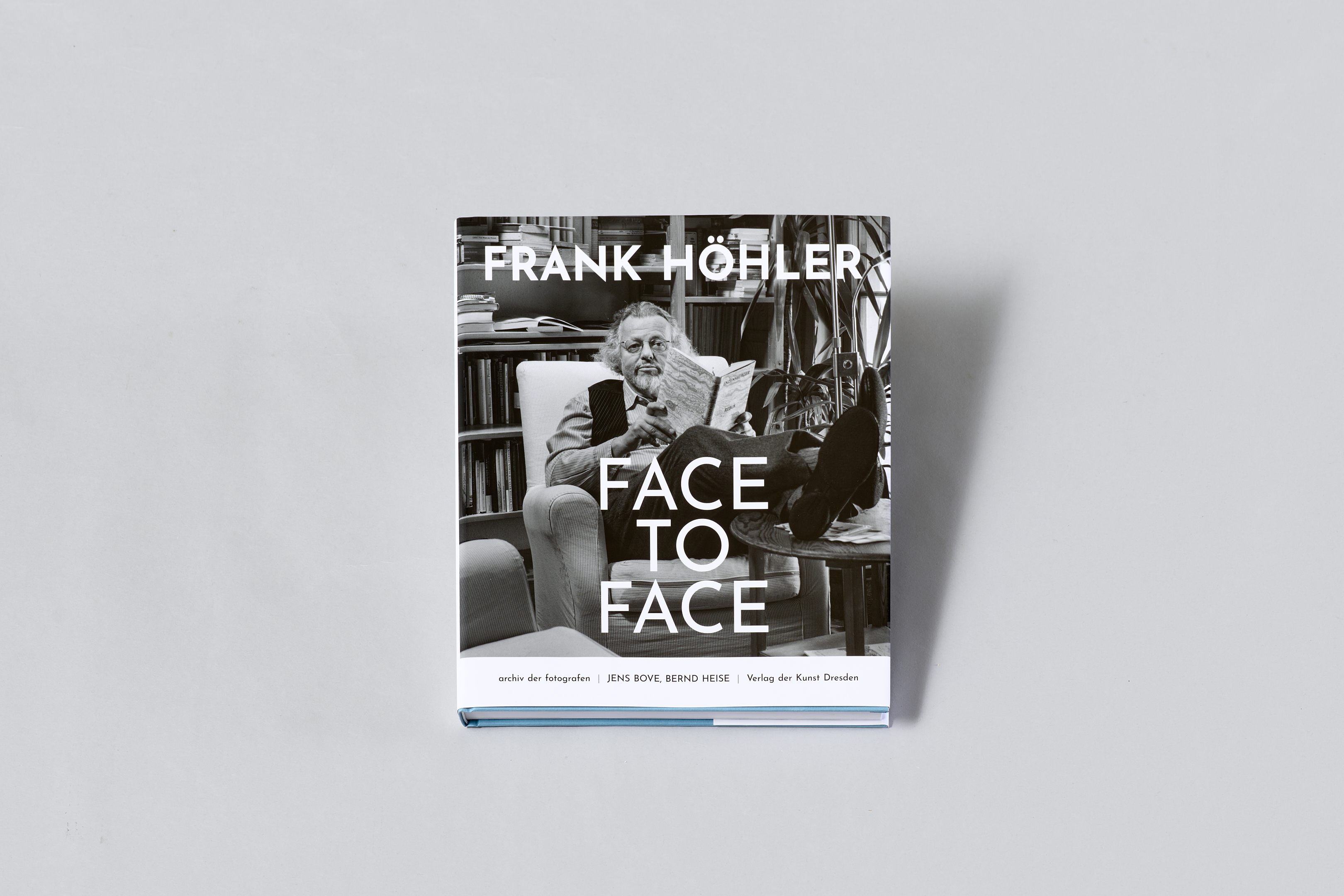 AI generated: The image shows the cover of a book entitled "Face to Face" by Frank Höhler. The cover shows a man in a cosy armchair reading a book and sitting in a room with bookshelves.